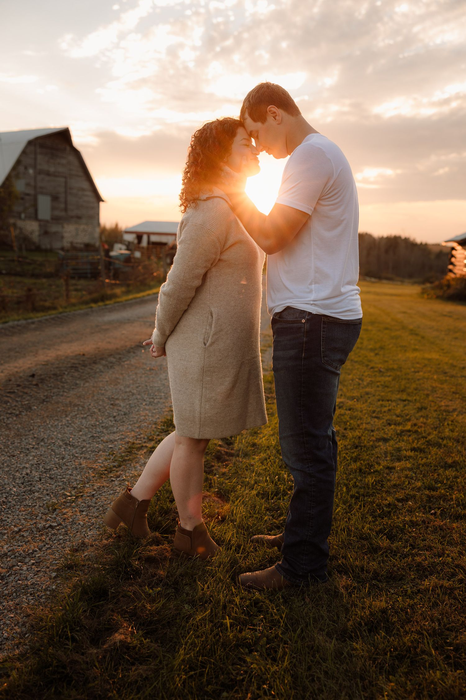 forehead to forehead hooding on to her neck with the sun in between them for engagement pictures in Escanaba, Michigan farm