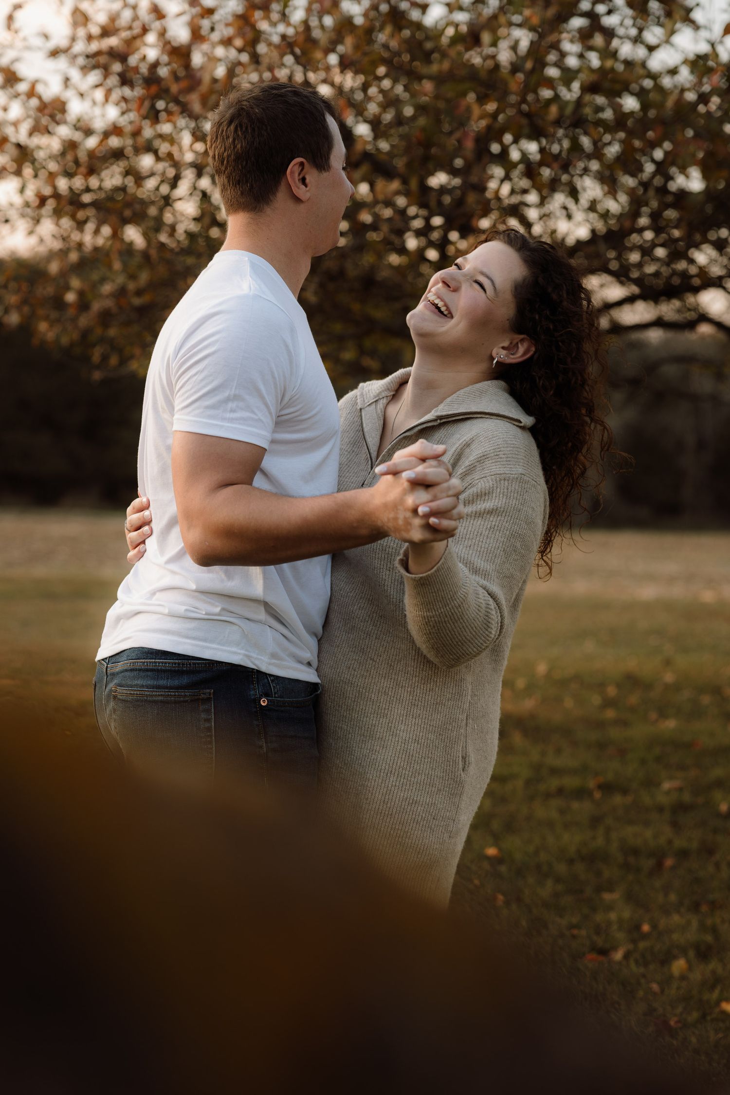 Engagement pictures in an apple orchard in Escanaba, Michigan couple dancing and laughing.