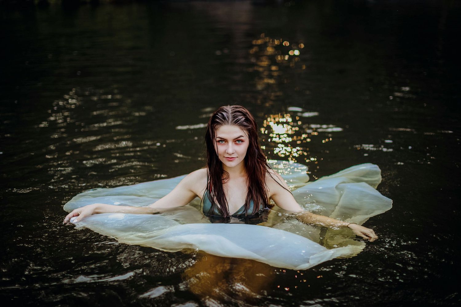 High school senior posing with her dress floating in front of a waterfall at Dead River Falls in Marquette, Michigan.