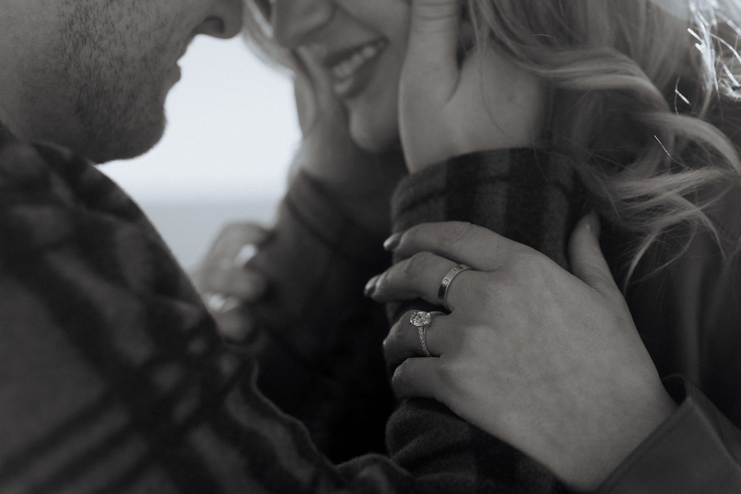 A couple shares an intimate moment in black and white, with hands gently touching.