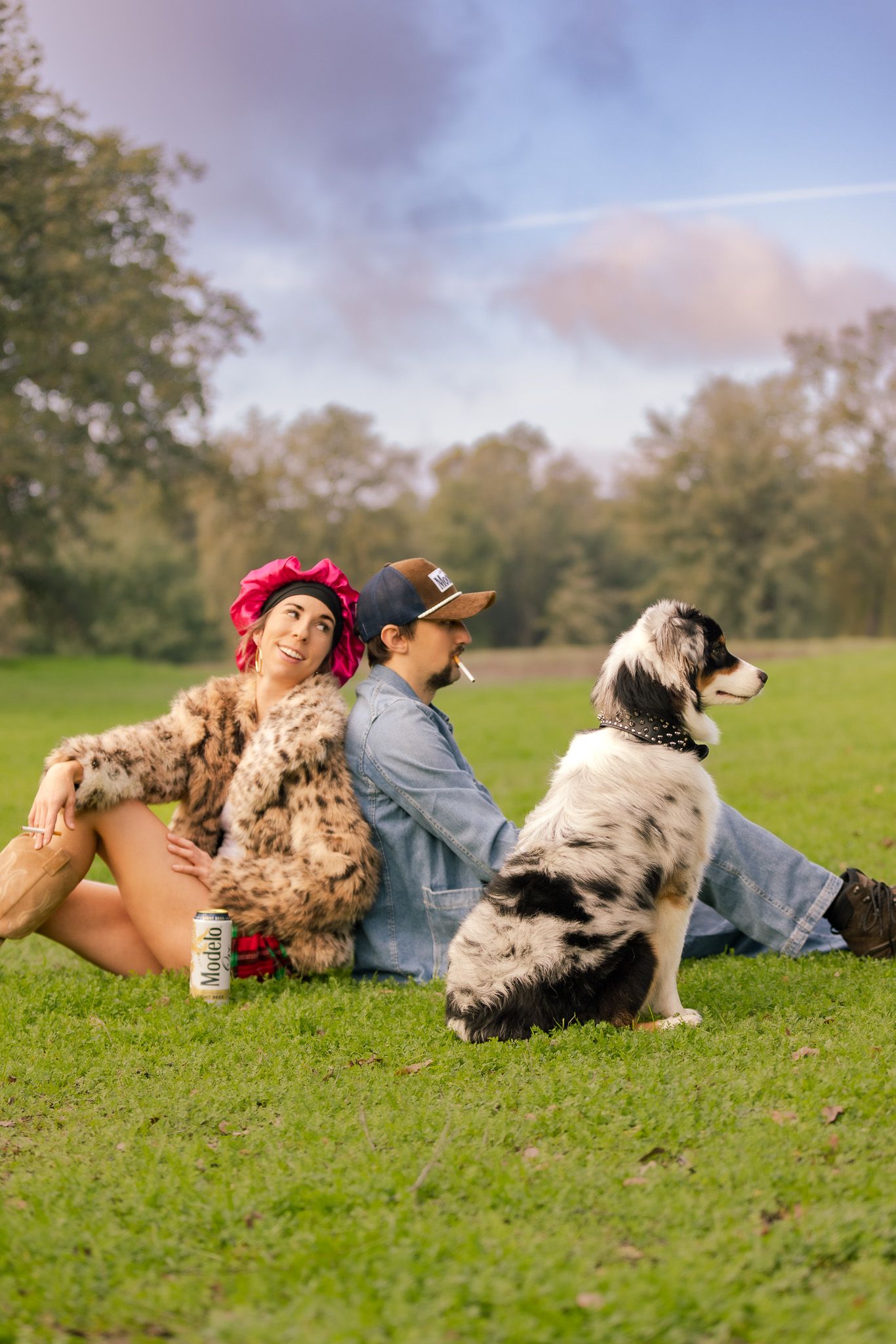 A person and their Australian Shepherd dog lie together on green grass during a peaceful autumn afternoon.