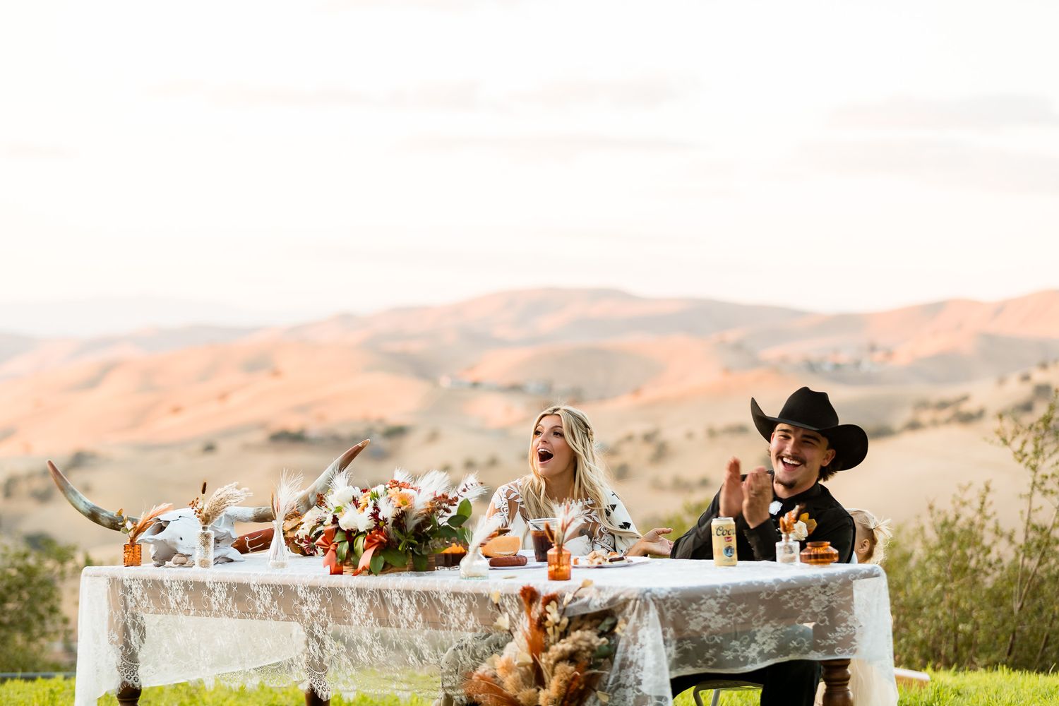 Wedding reception table set against rolling hills with autumn floral arrangements.