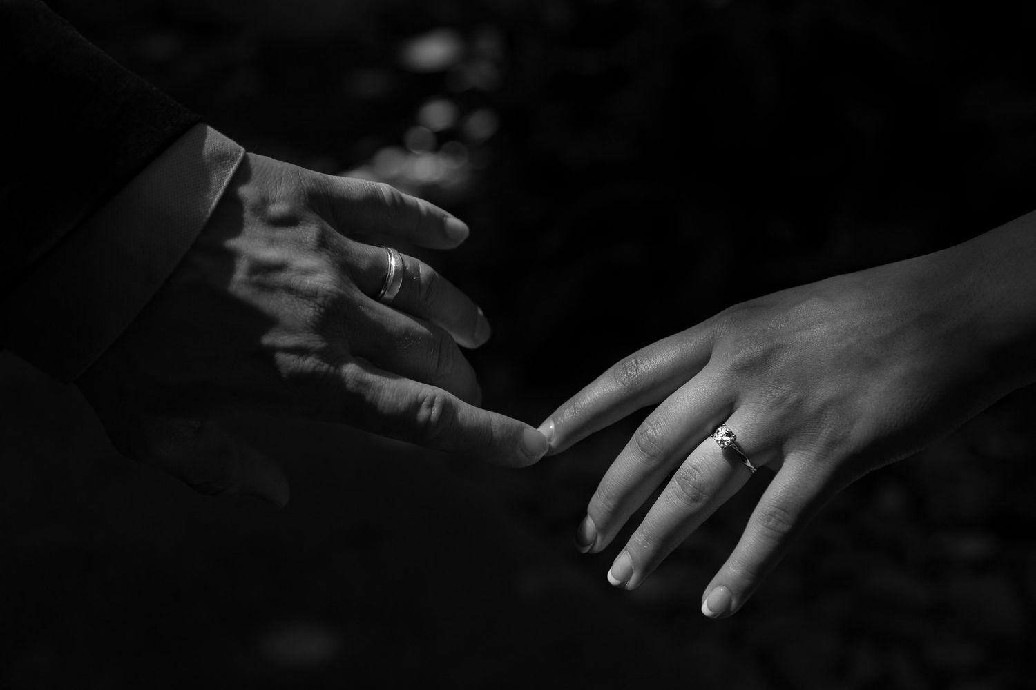 Intimate black and white photograph of hands reaching toward each other.
