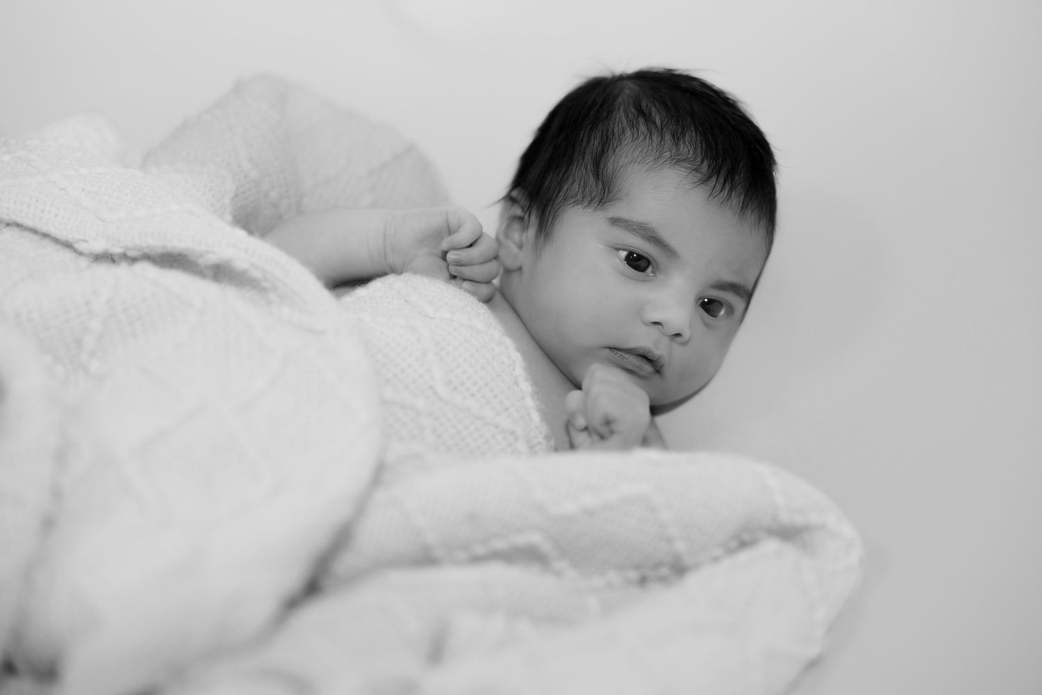 A black and white photo montage shows a baby resting in different positions on soft blankets.