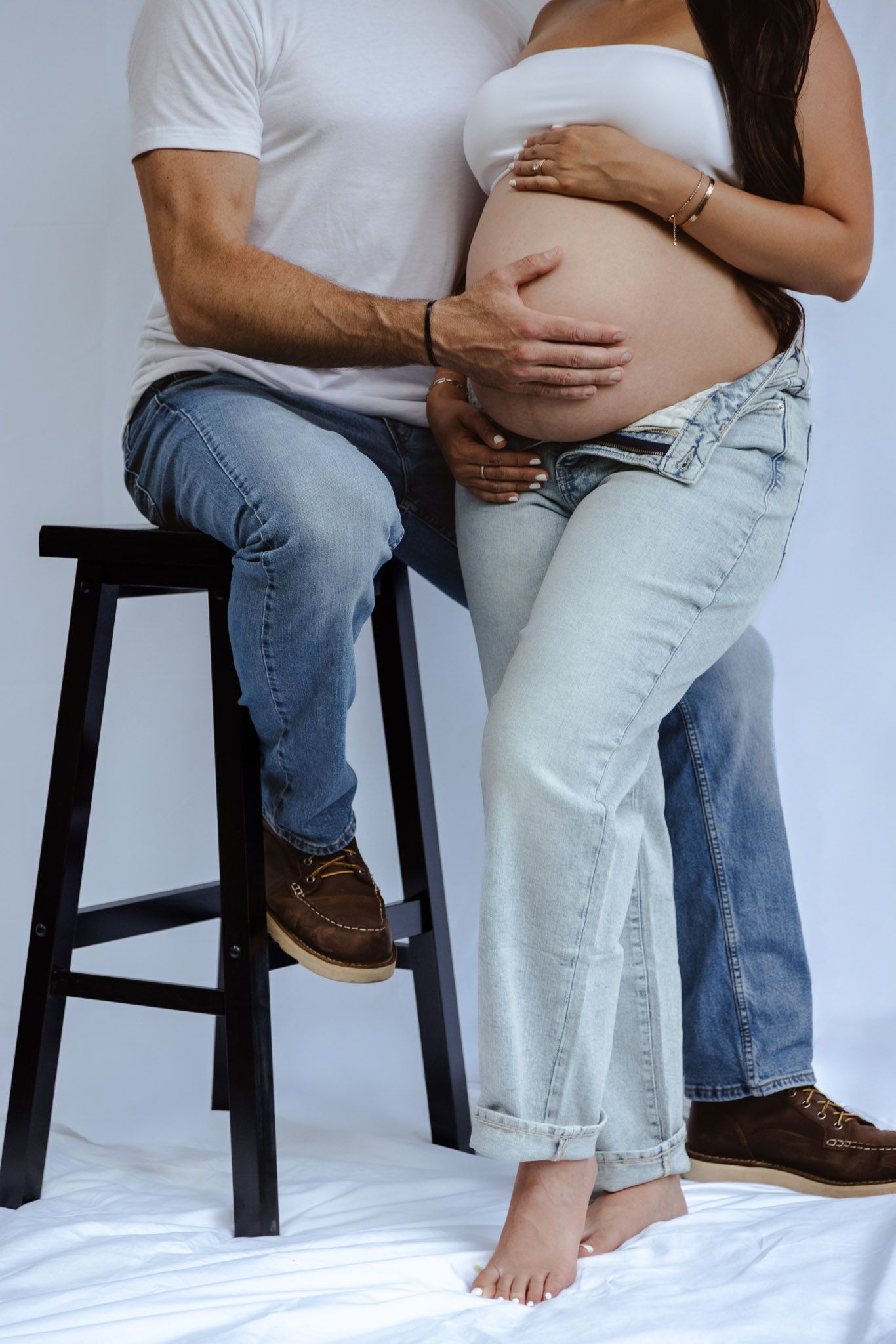 Four sequential photos showing a pregnant woman's belly with a person sitting on a stool beside her in casual attire.