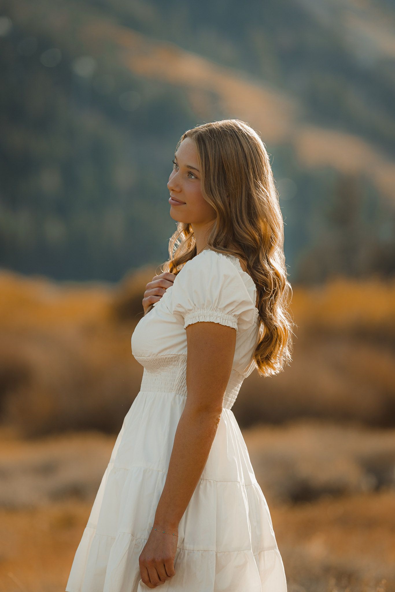 White dress silhouette against golden mountain landscape at sunset.