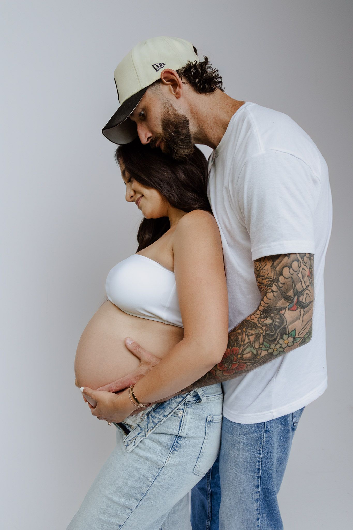 A series of maternity photos showing a couple embracing, with focus on the pregnant belly in light and neutral tones.