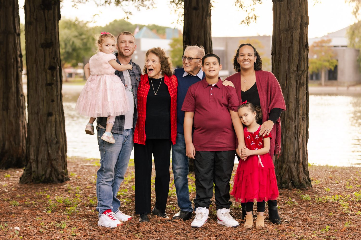 Large family group wearing red and black clothing poses together for outdoor autumn portrait.