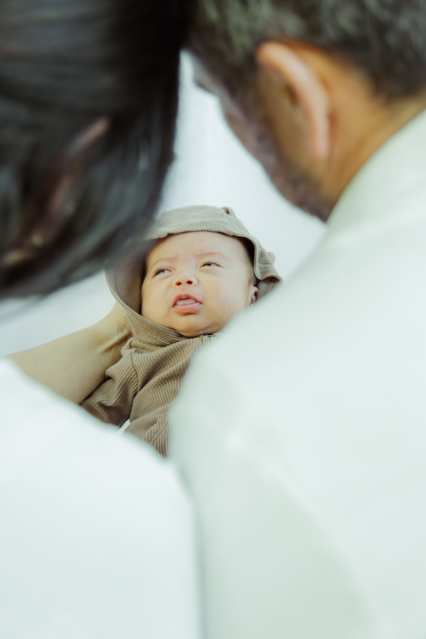 A sleeping baby in a white blanket with soft lighting creates a peaceful and serene atmosphere.