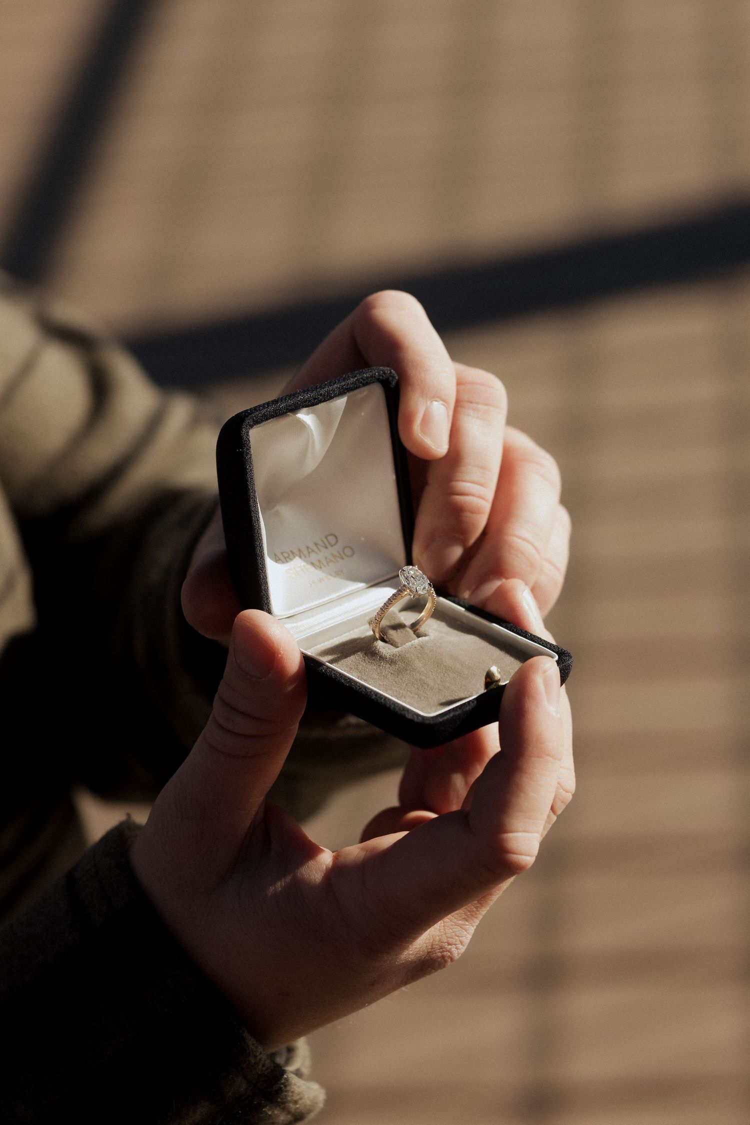 Hands opening a small black ring box in a sequence of photos showing the reveal of an engagement ring.