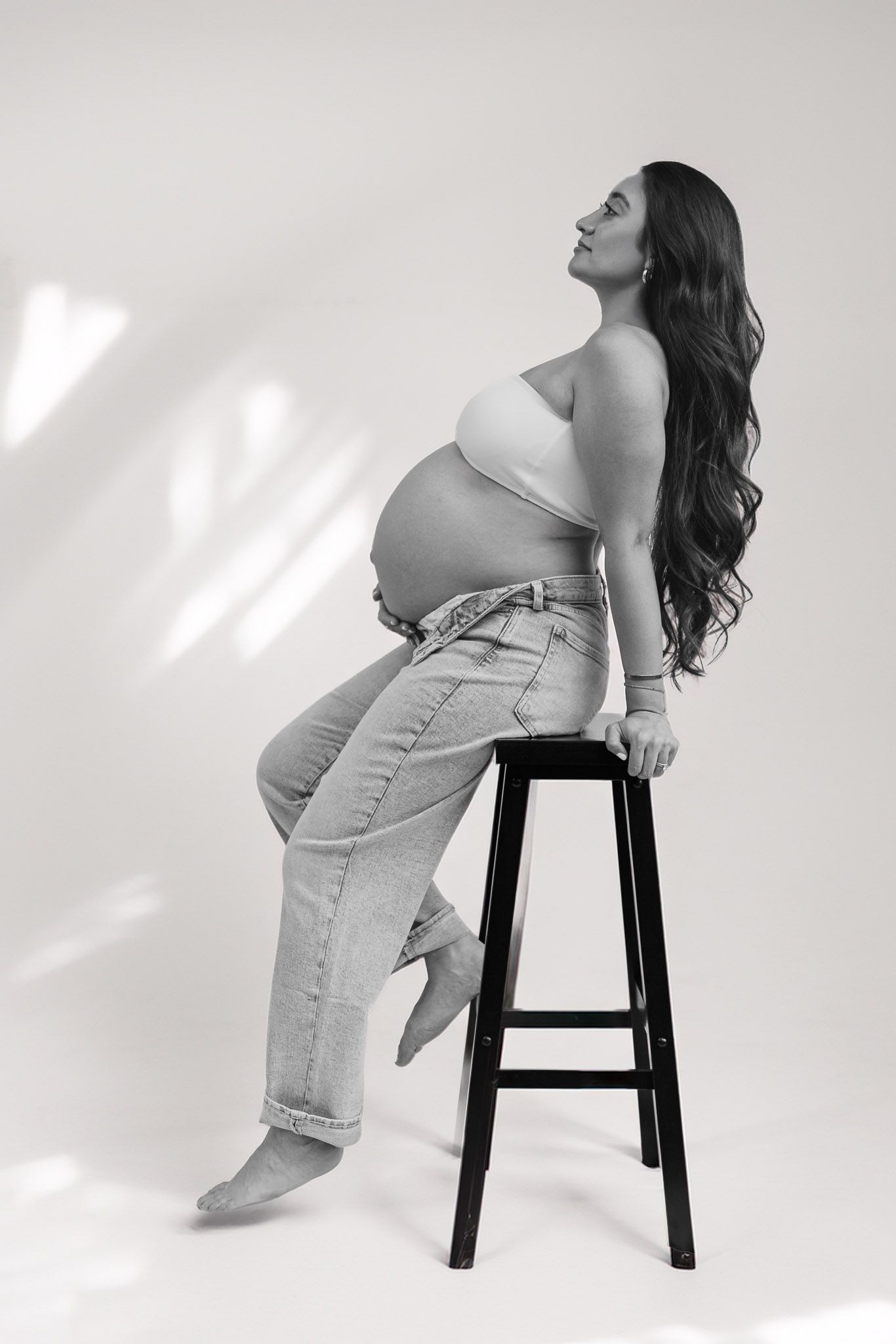 A black and white photo series showing a person in jeans posing on a stool against a white background.