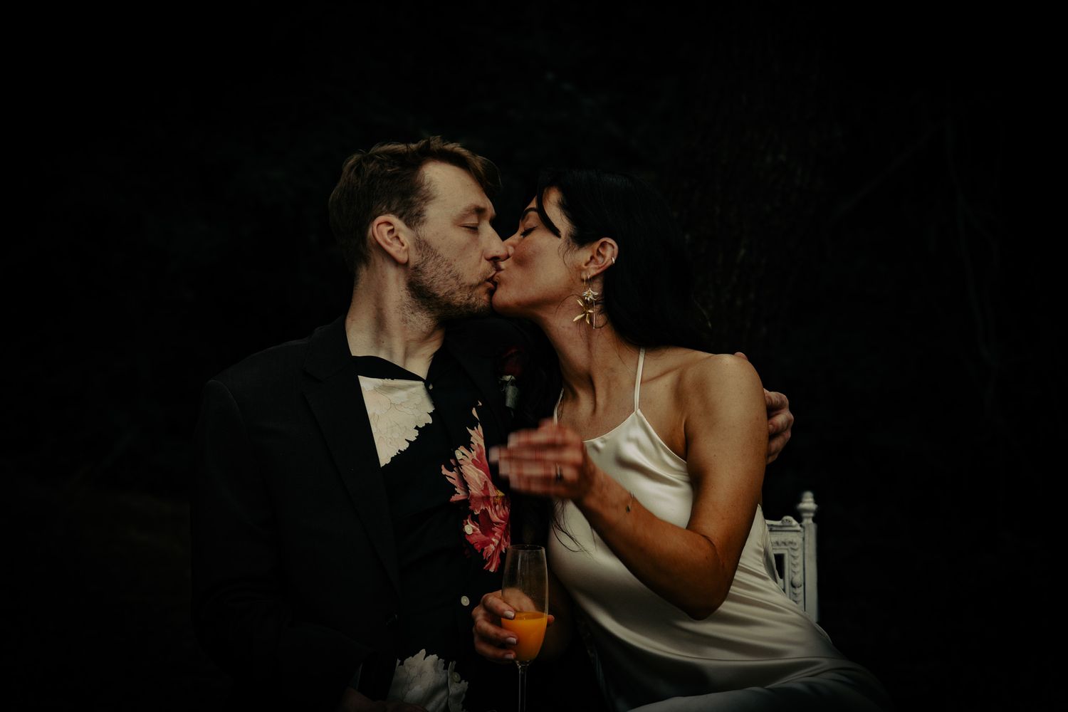 Dramatic low-light wedding portraits with dark background and romantic poses.