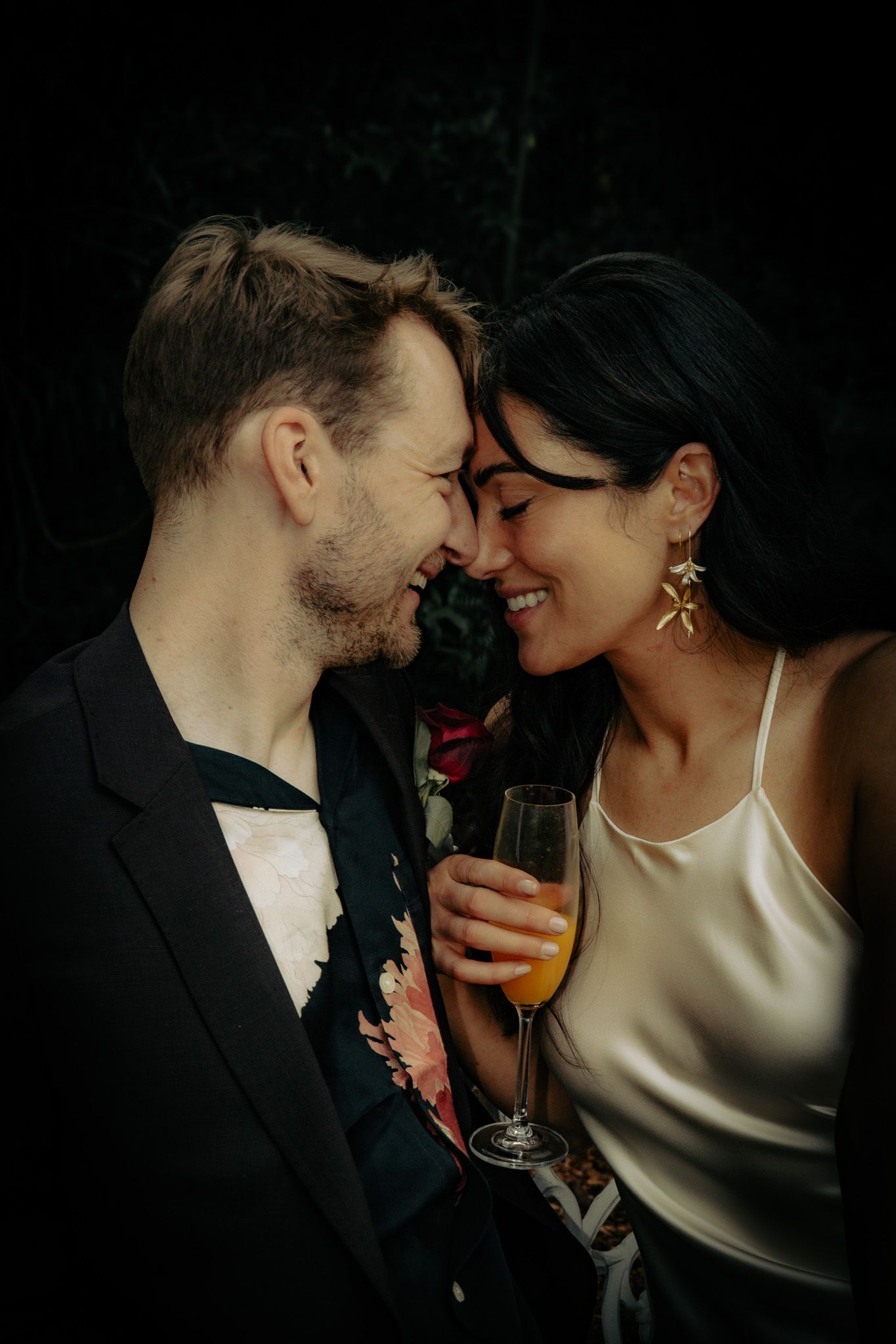An intimate moment shared between a couple with champagne against a dark background.