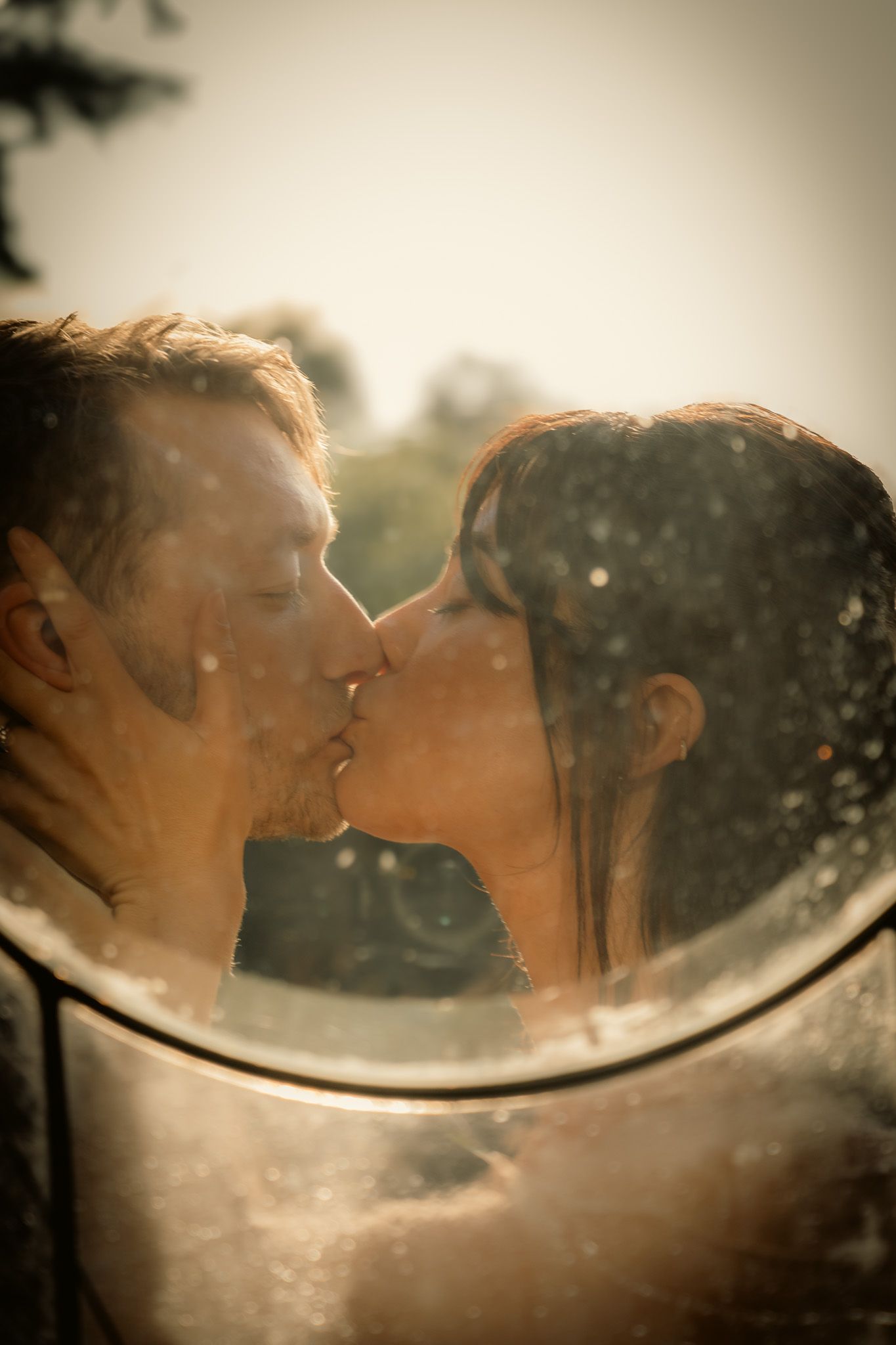 Romantic sepia-toned reflection of couple kissing in mirror outdoors.