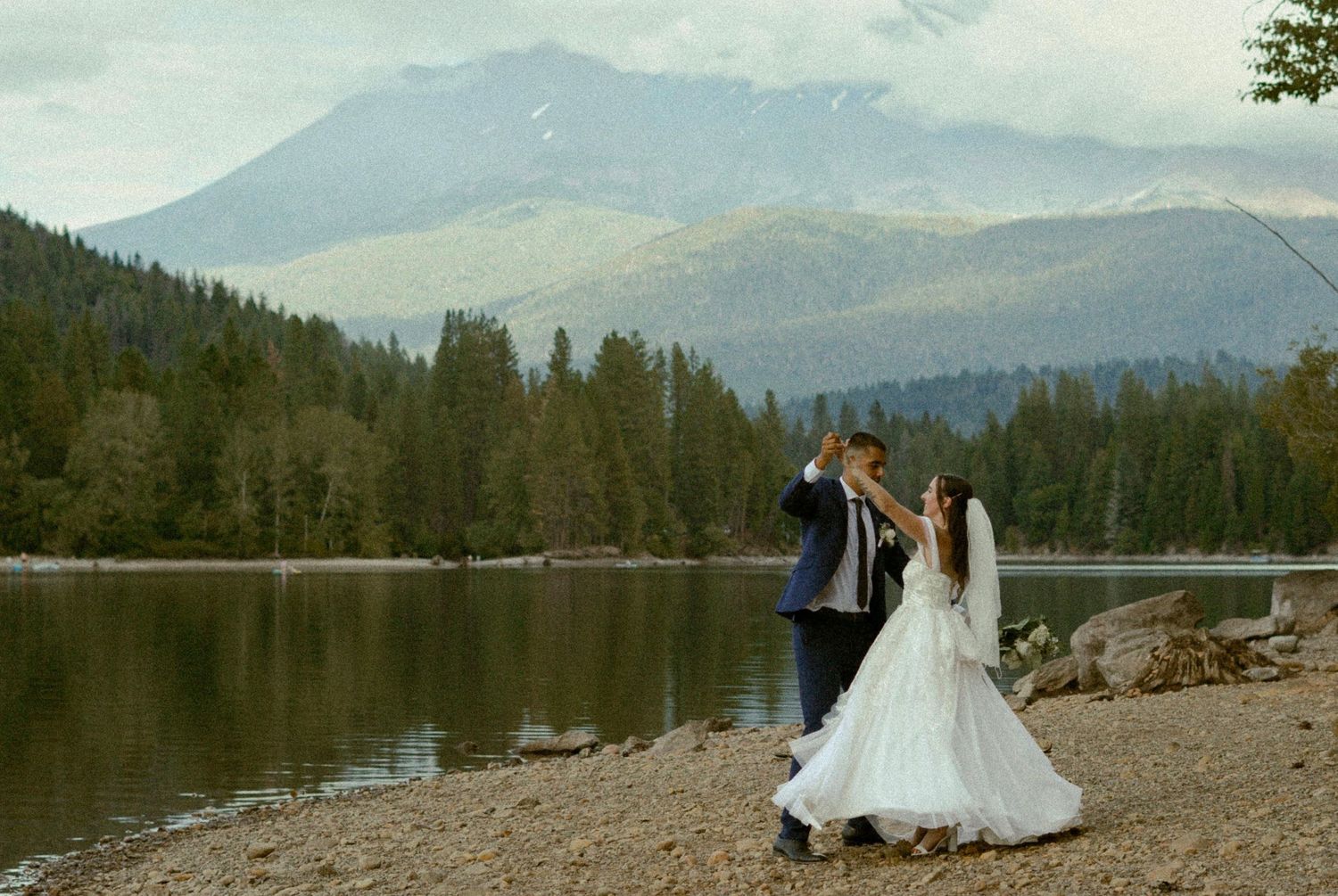 Wedding couple poses against scenic mountain lake backdrop in romantic shots.