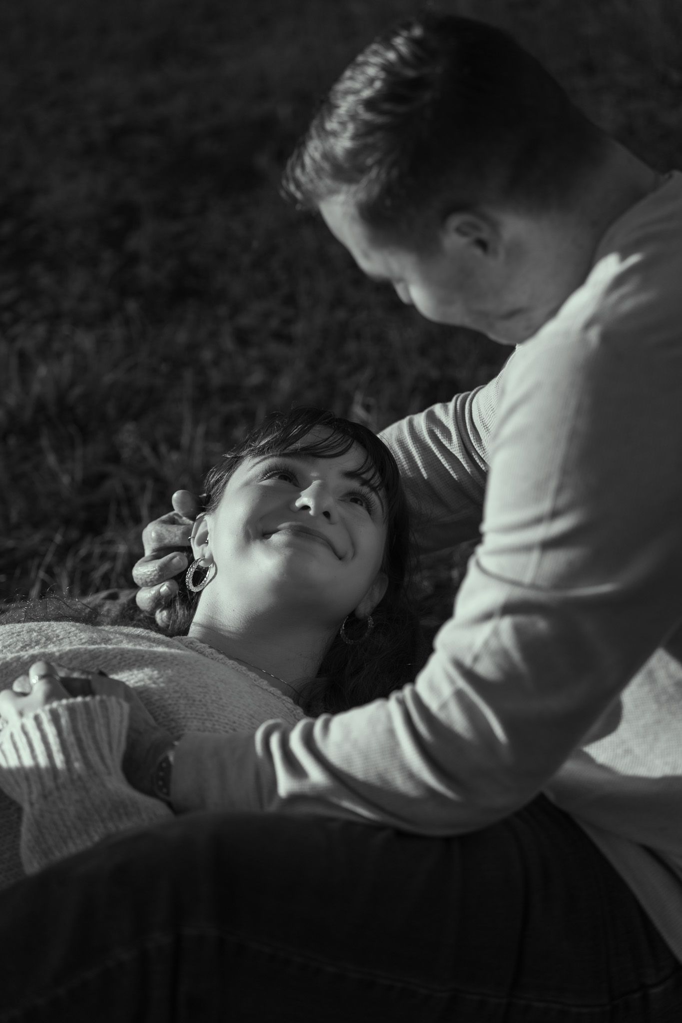 Black and white sequence showing a parent comforting a child laying down in a tender moment of connection.