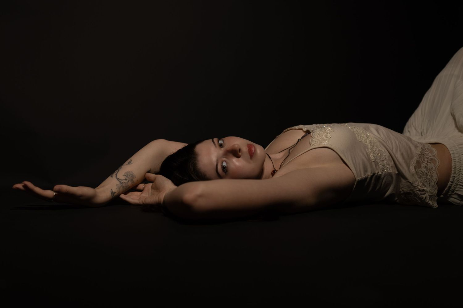 A dramatic black and white photo series showing a figure reclining in artistic poses against a dark background.