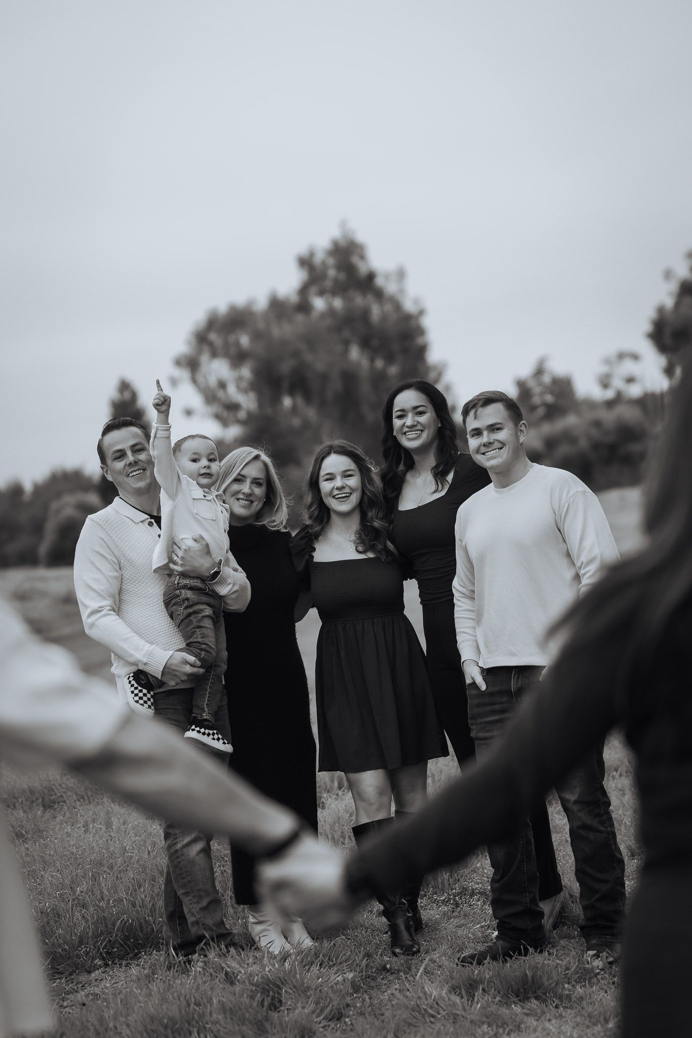 Black and white candid family photo showing joyful interaction in an outdoor setting.