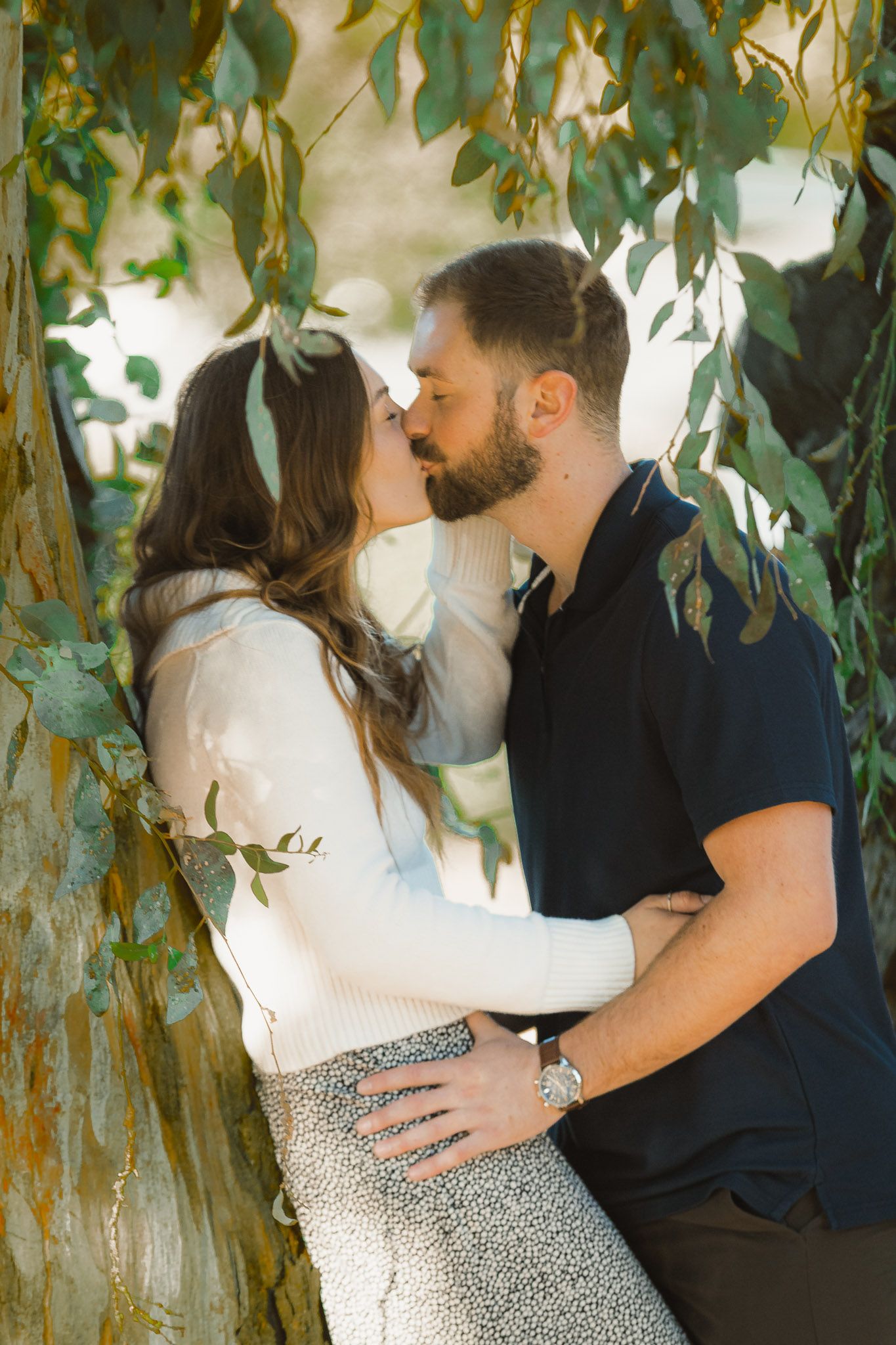 A romantic couple embraces under green leaves in a series of intimate outdoor portrait photos.