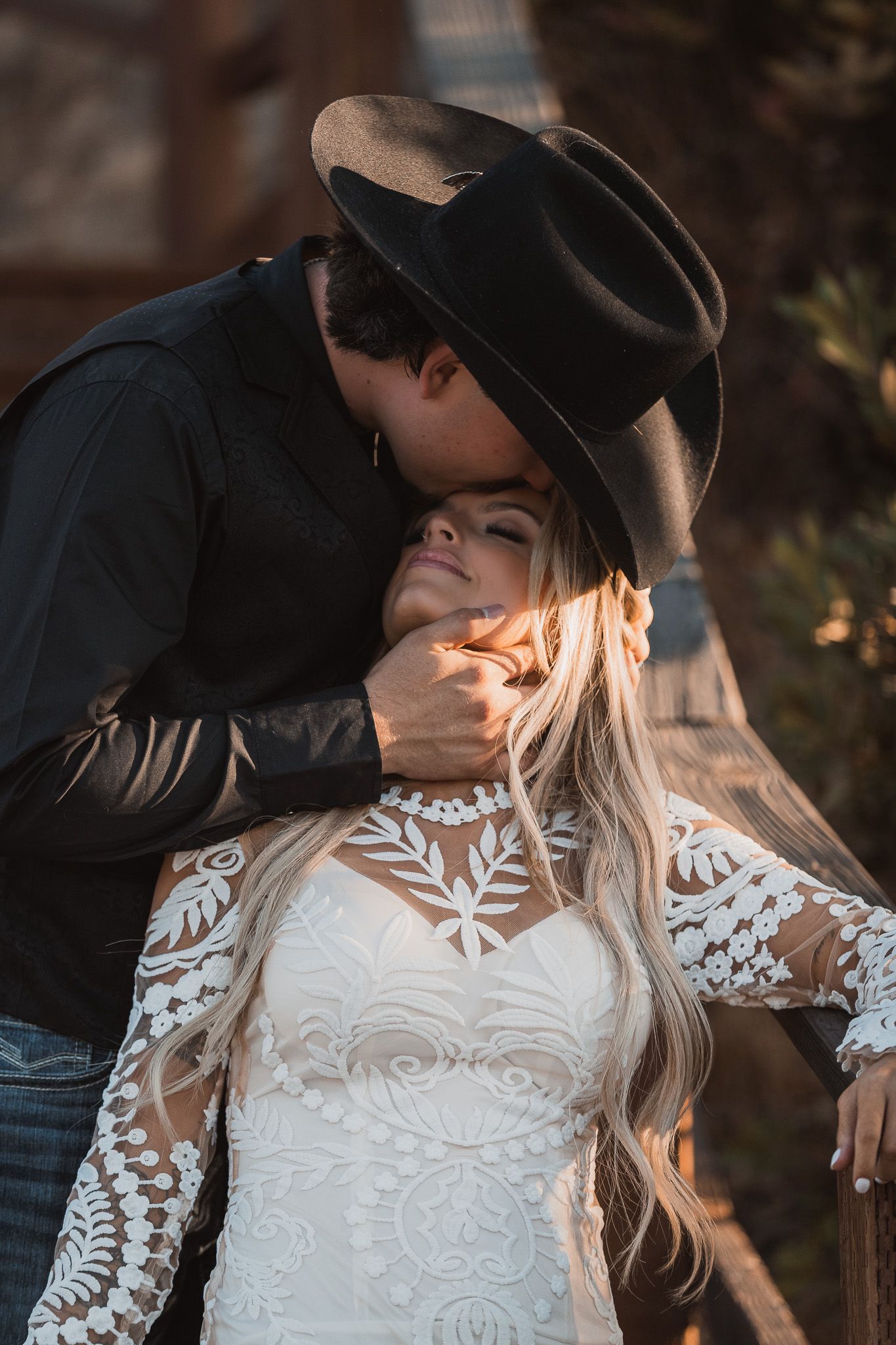 Intimate moment between newlyweds in western attire during sunset photoshoot.