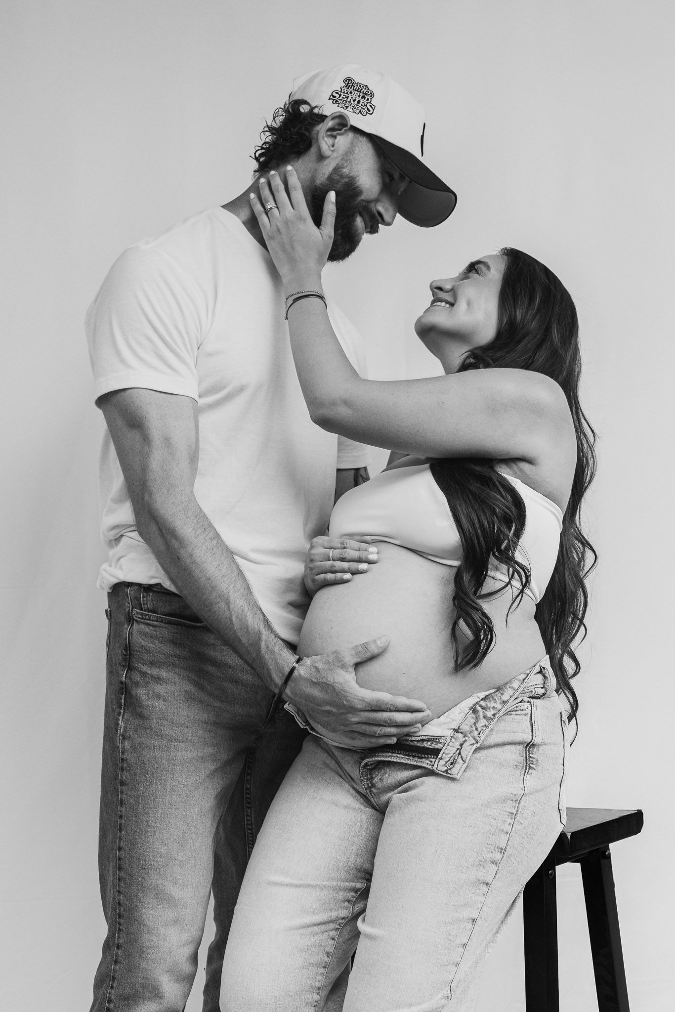 Black and white maternity photos capturing intimate moments between couple in studio setting.