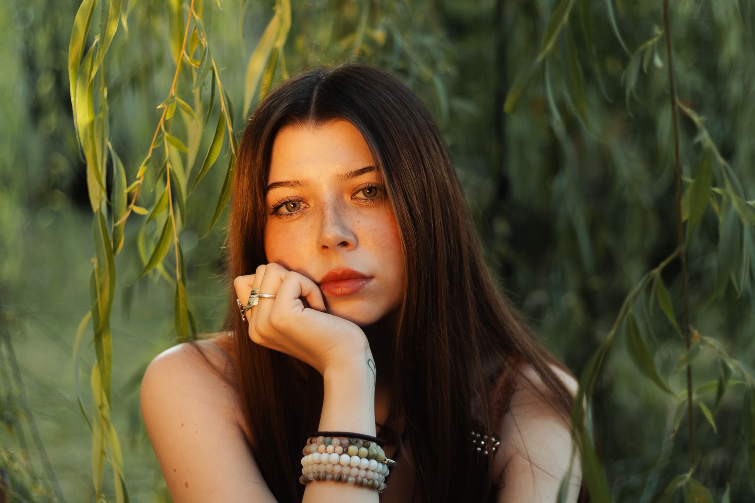 A series of six outdoor portraits with hanging willow branches and natural greenery in the background.