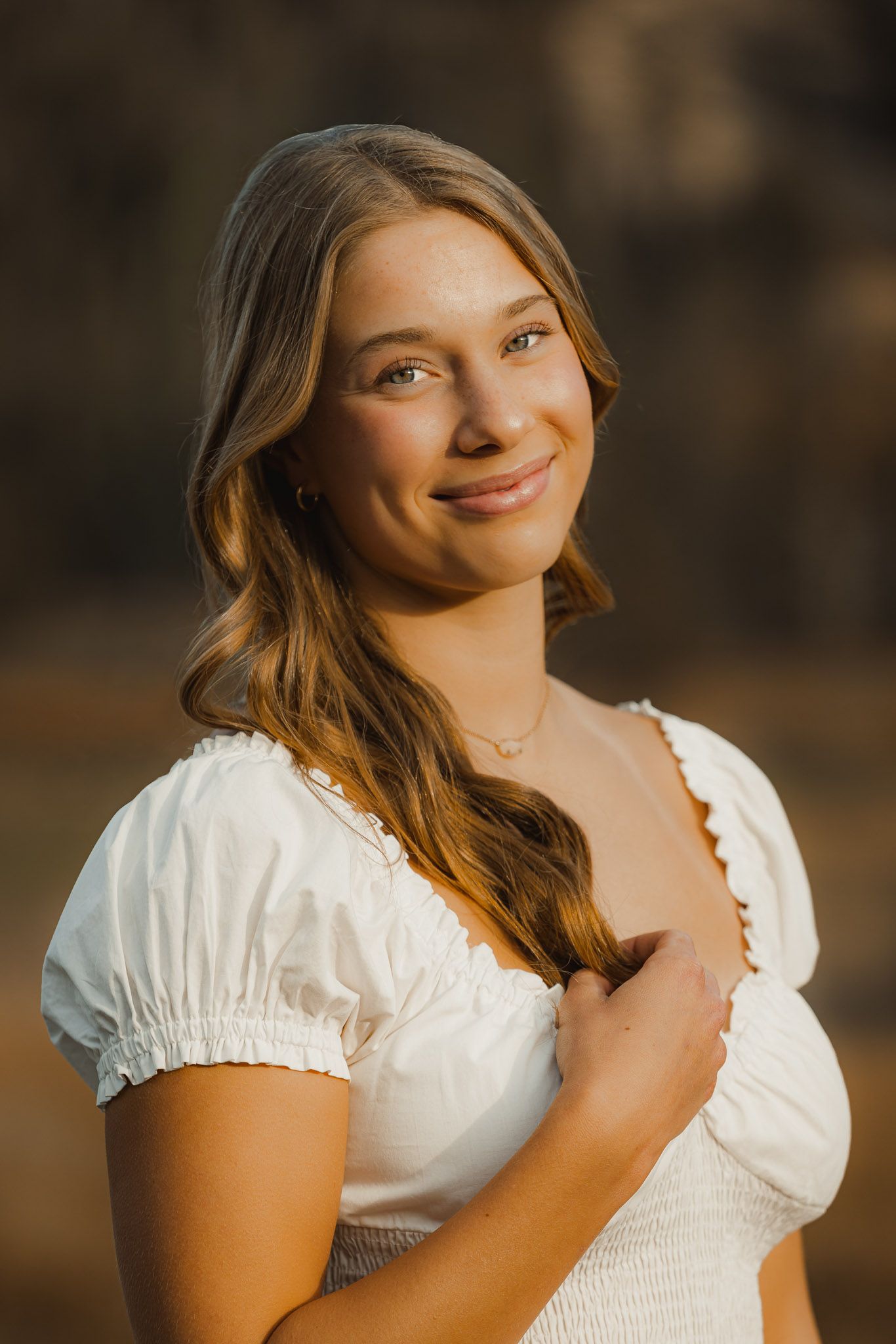 Portrait in soft golden lighting wearing white peasant-style dress.