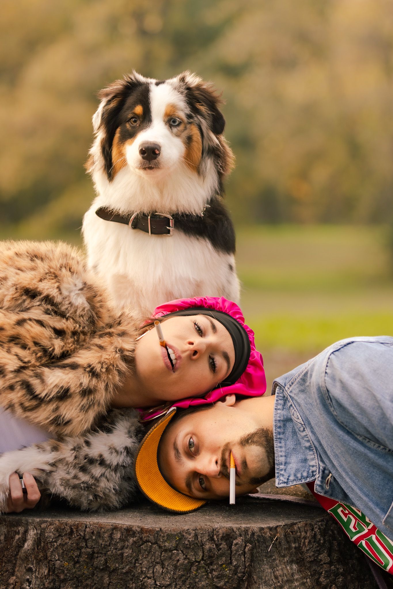 An Australian Shepherd dog and companion share a tender moment while resting together outdoors.