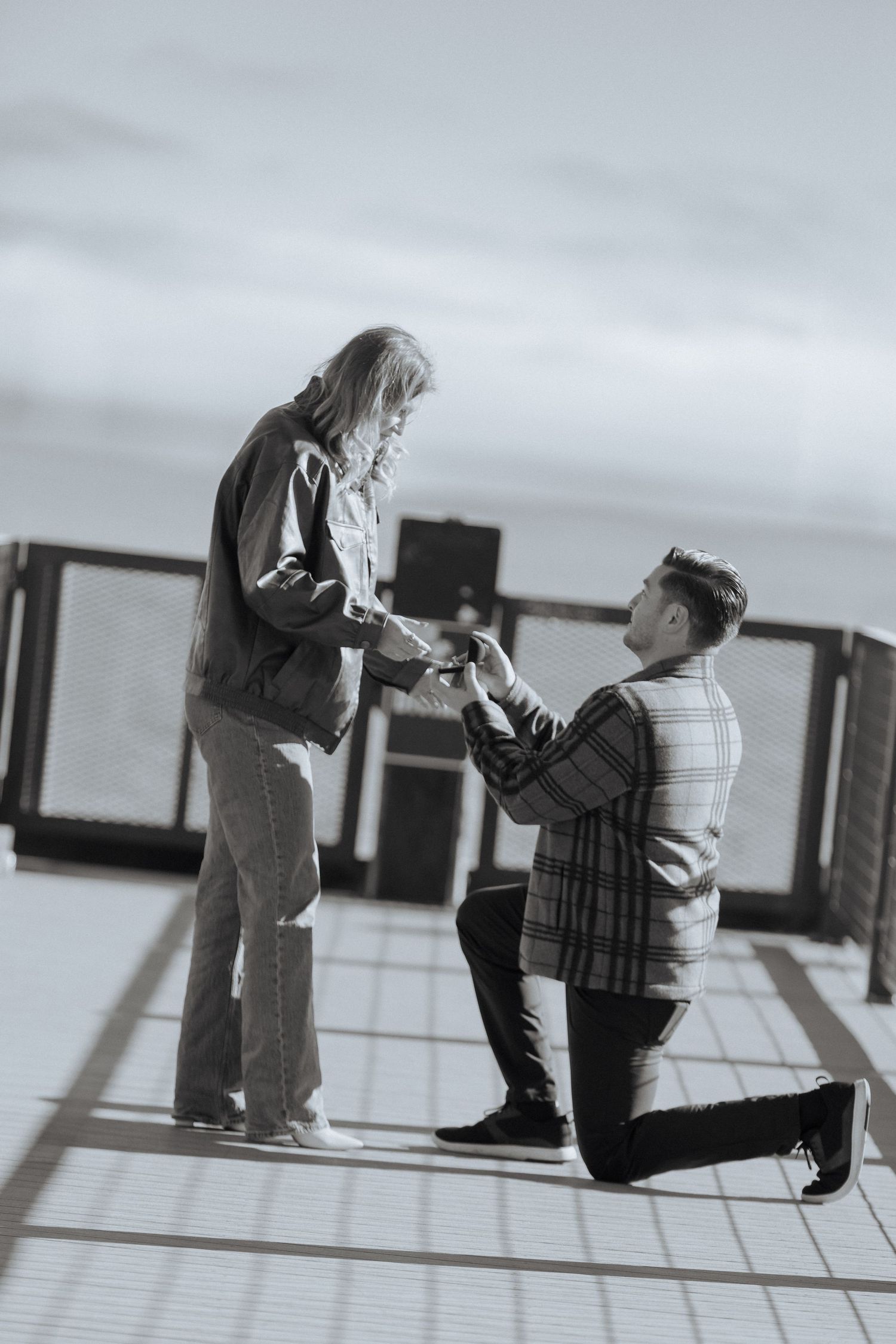 A sequence of black and white photos showing a romantic proposal moment on a tiled floor.