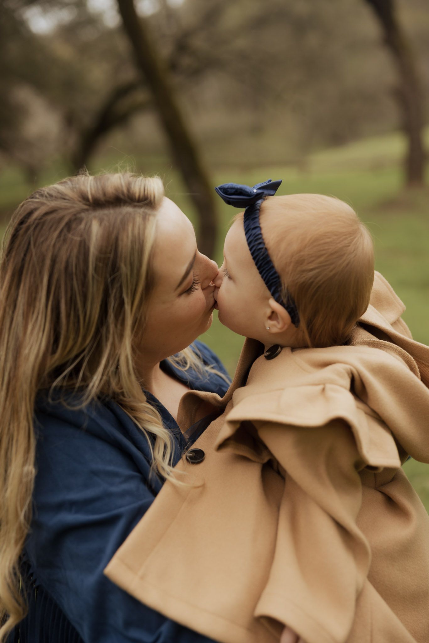 Parent and child in matching navy and tan outfits share playful moments in nature.