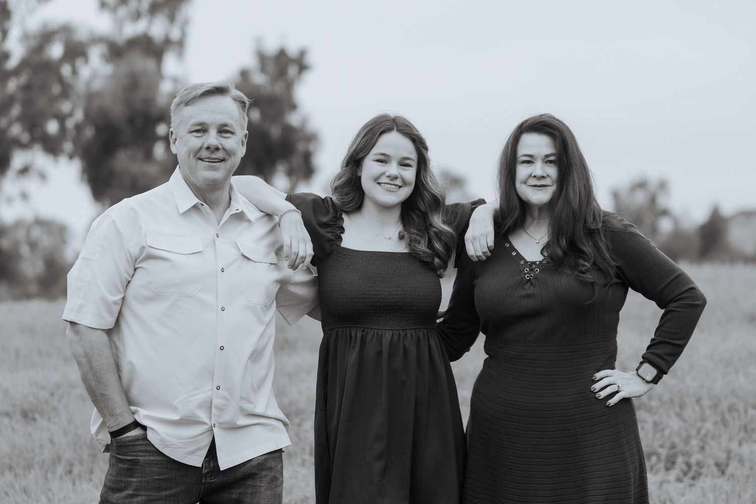 A series of black and white outdoor family portraits showing people smiling and embracing in a natural setting.