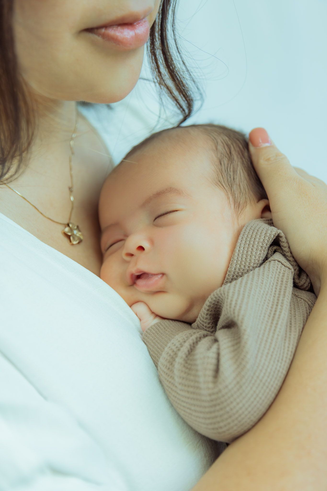 A tender moment of a sleeping baby in striped clothing nestled against a caregiver.
