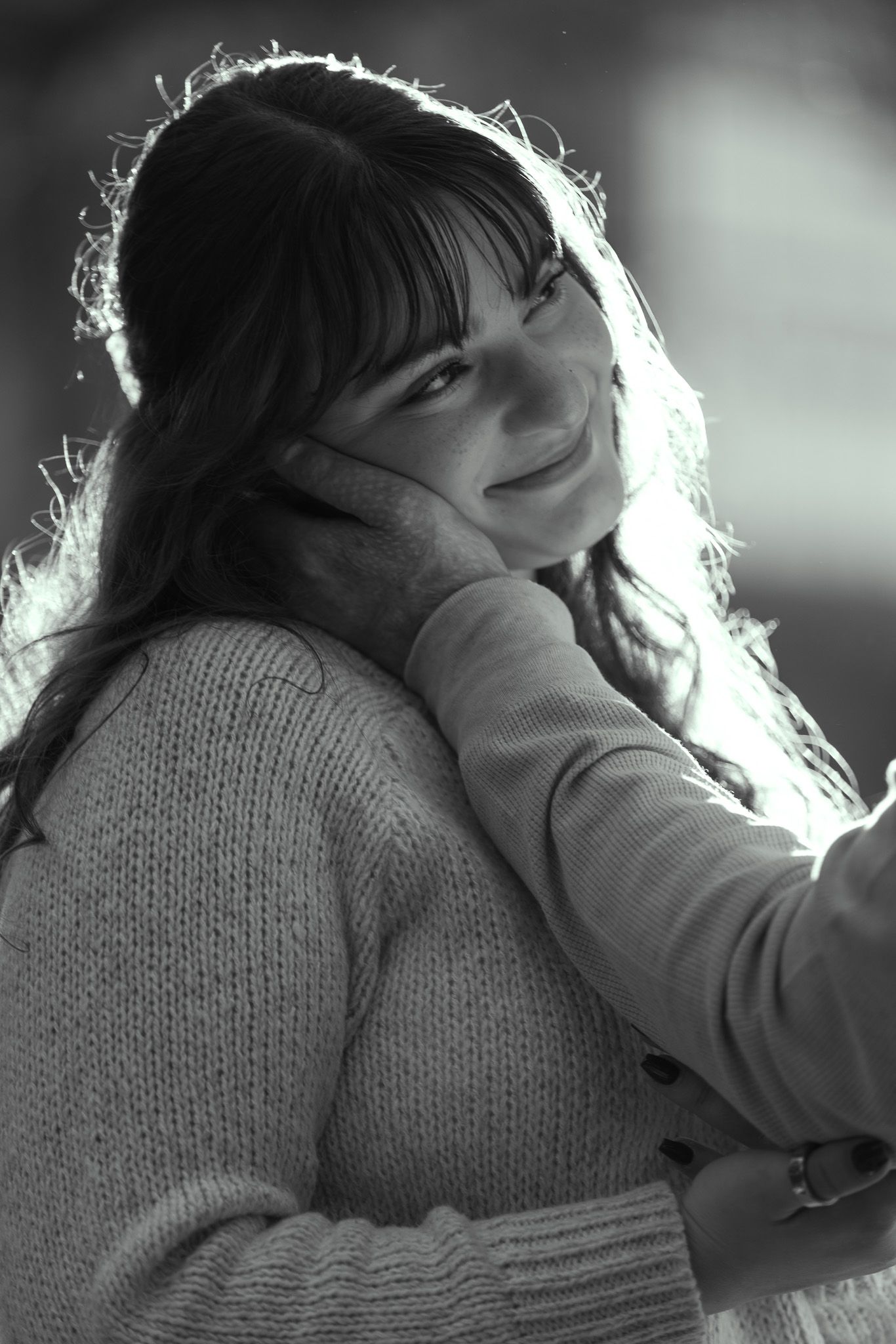 A series of black and white romantic photos showing a couple in intimate moments wearing cozy sweaters.