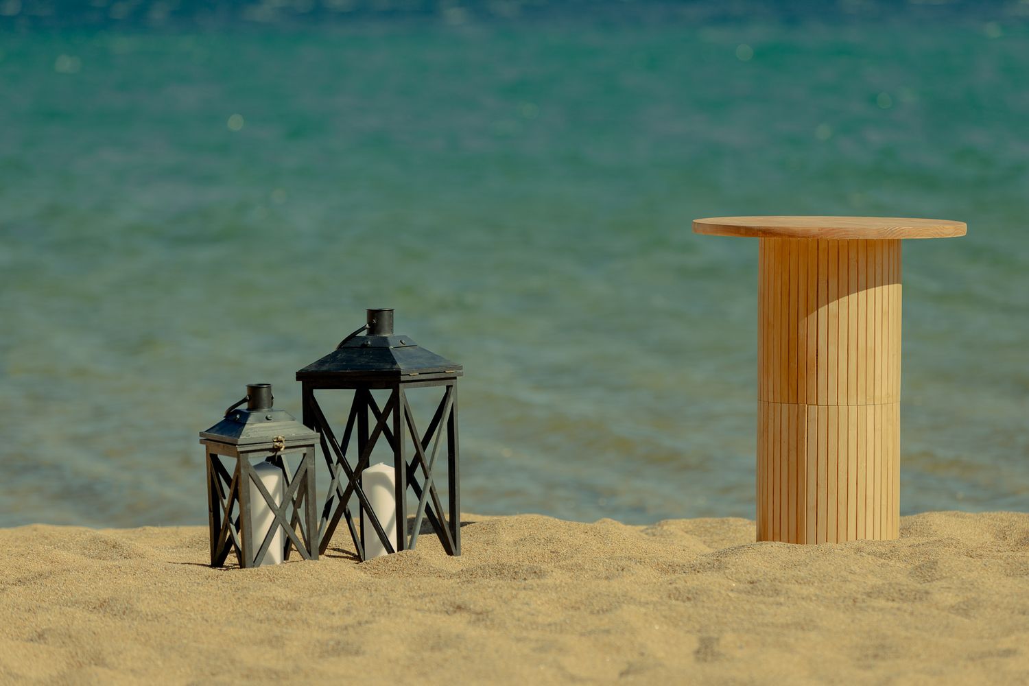 Wooden columns and chairs set up on a sandy beach with crystal clear turquoise waters.