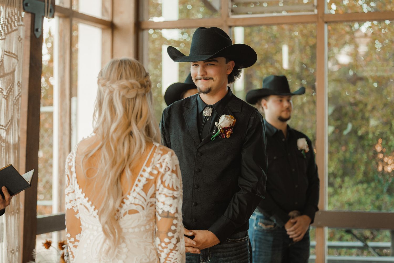 Wedding ceremony moment with western attire and rustic indoor setting.