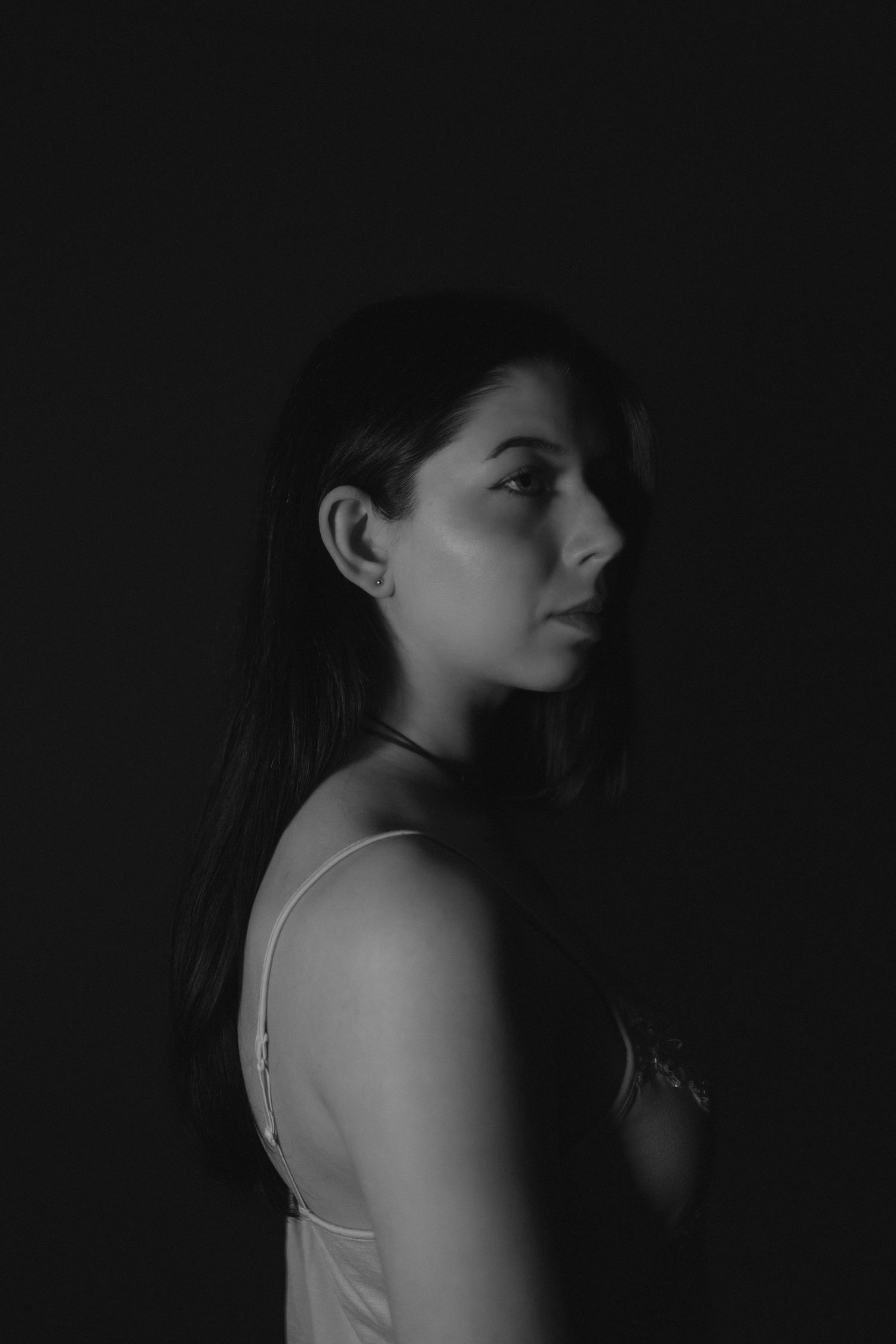 A dramatic black and white portrait series showing different angles of a figure in shadow against a dark background.