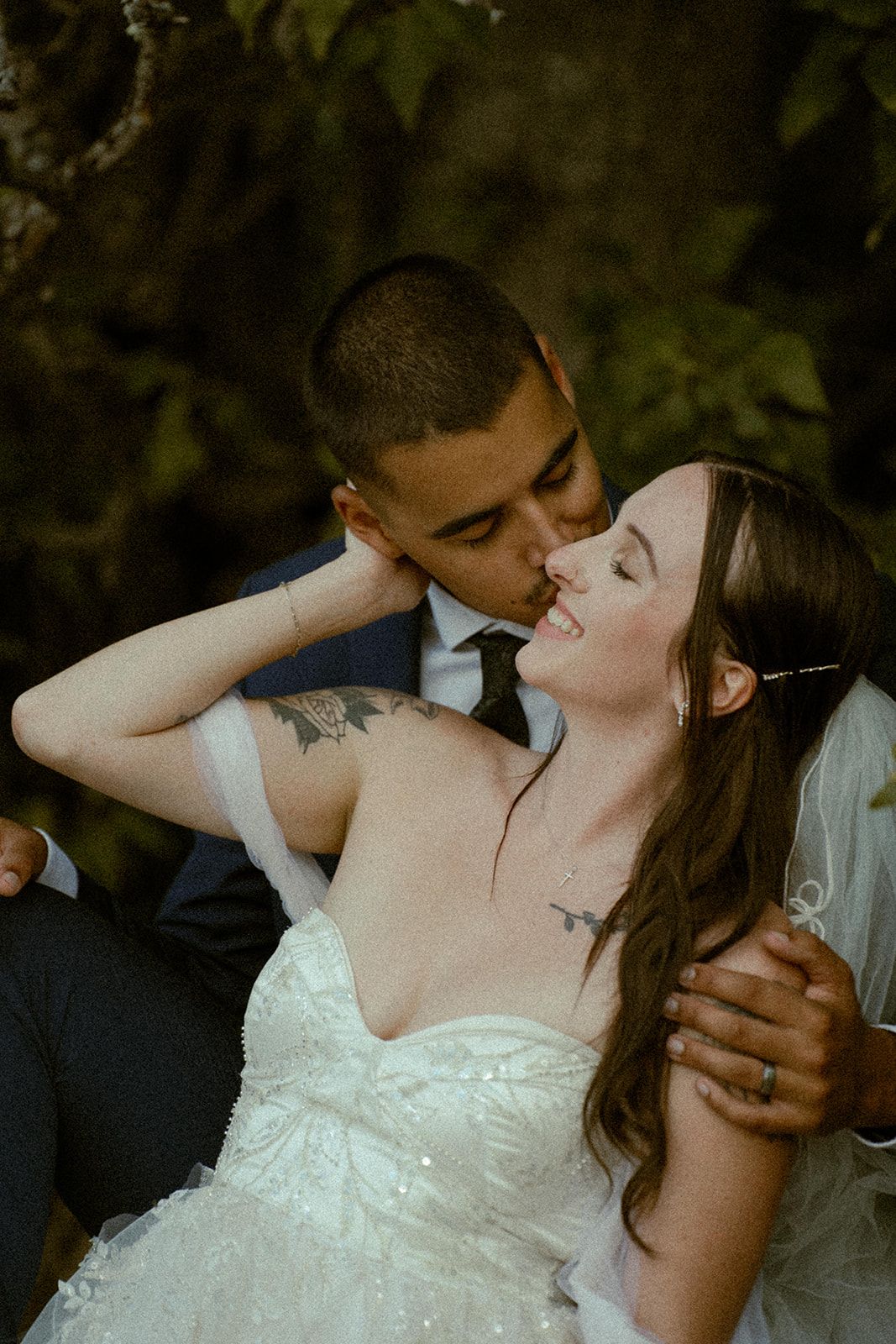 Romantic wedding couple shares intimate moments in natural outdoor setting.