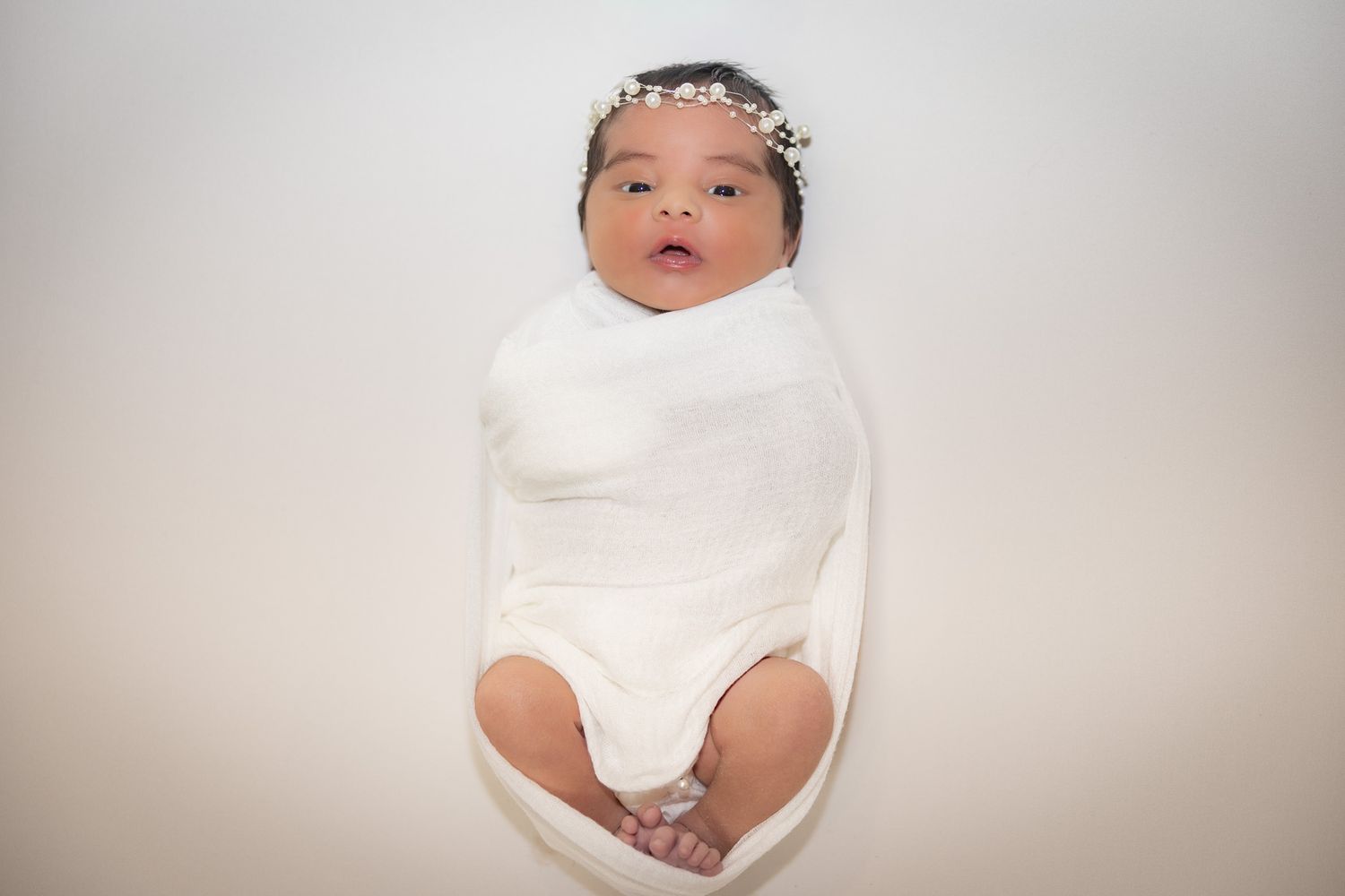 Baby wearing white onesie sits and poses for multiple sequential photos in a studio setting.
