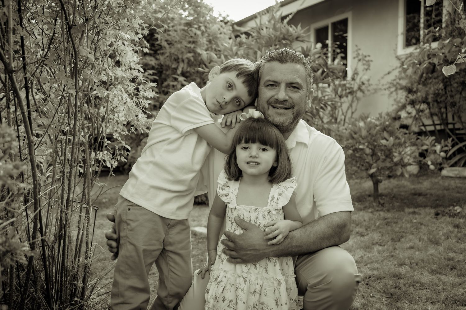 A series of black and white vintage-style family photographs showing tender moments in an outdoor garden setting.