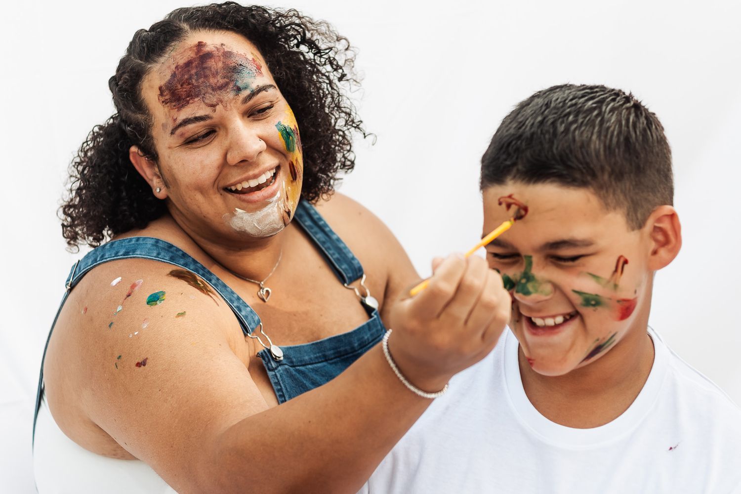 Playful couple with colorful paint on their faces laughing together.