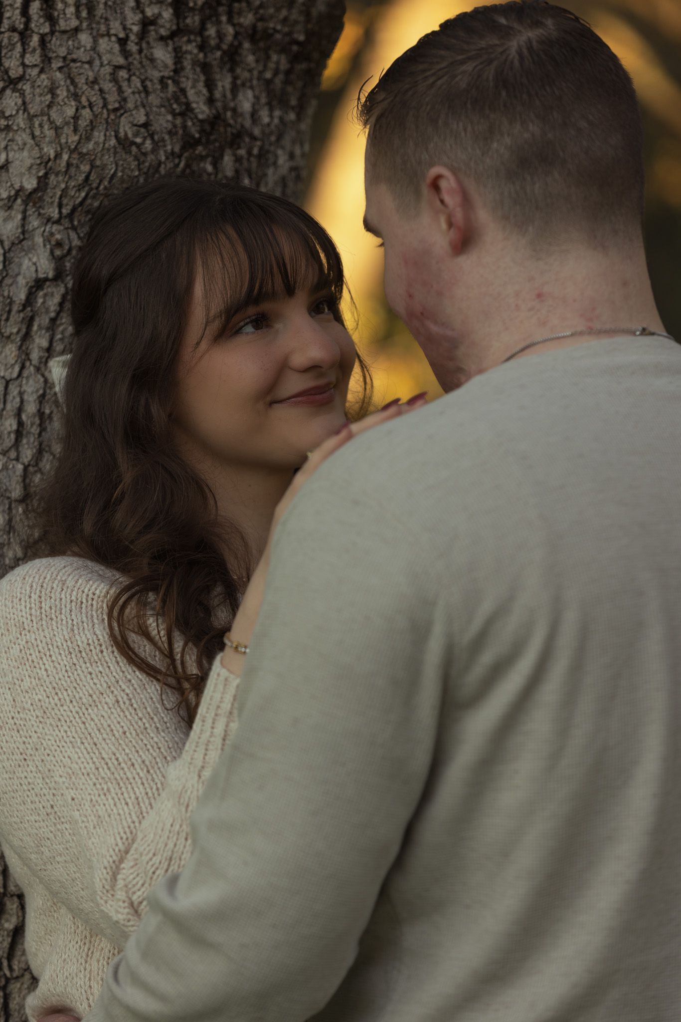 A romantic sequence of photos showing a couple embracing against a tree in warm lighting.