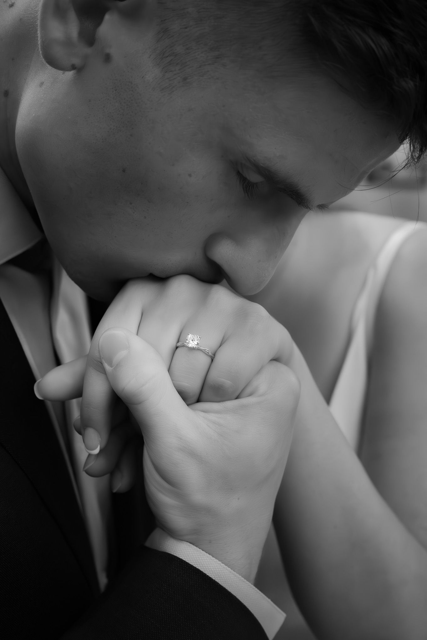 Black and white intimate wedding moment with focus on hands and ring.
