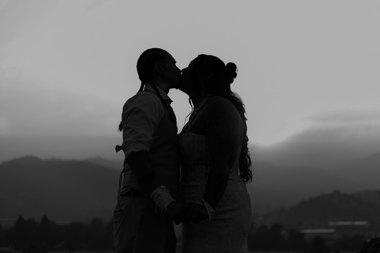 Silhouettes of a couple against a dramatic mountain landscape at sunset.