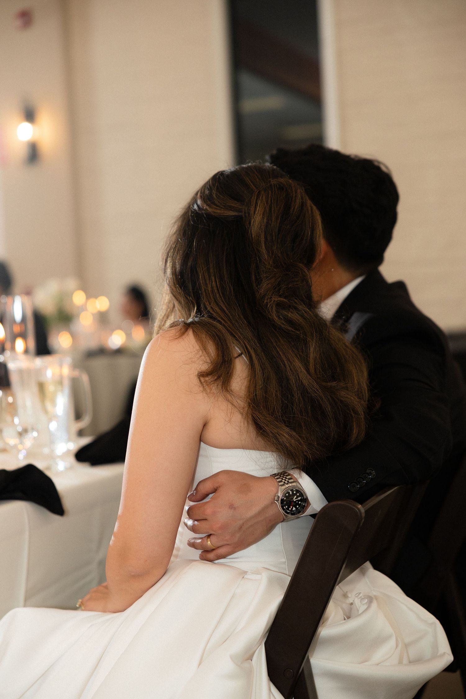 Bride and groom sharing intimate moment at wedding reception sweetheart table.