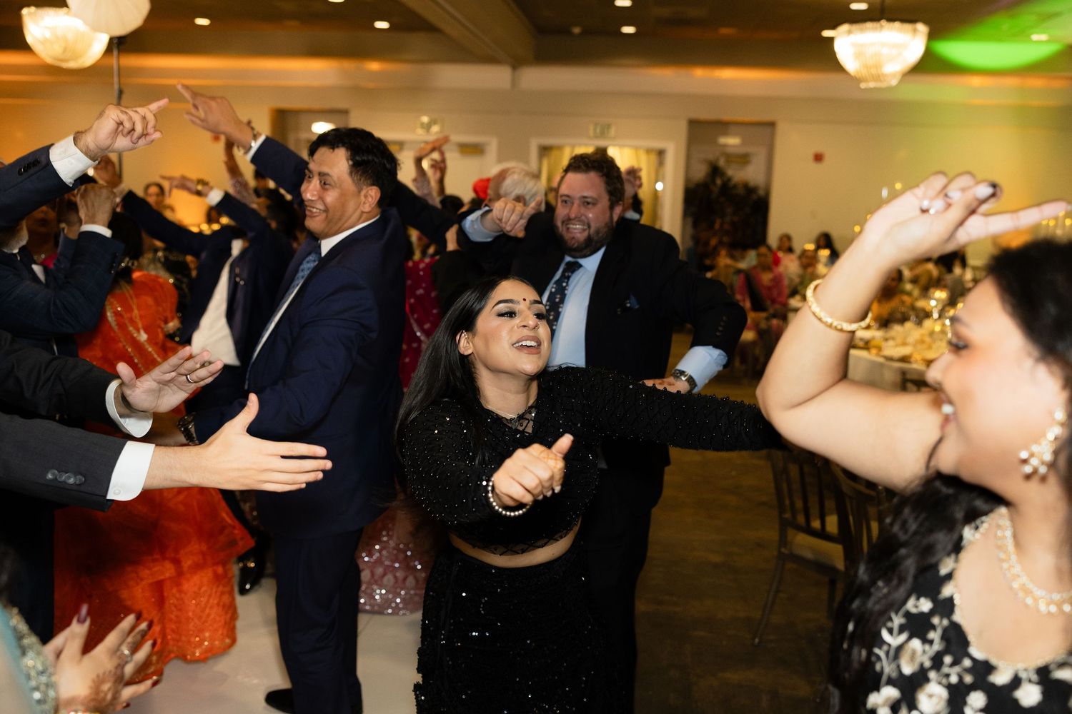 People dancing and socializing at an indoor wedding reception with atmospheric lighting.