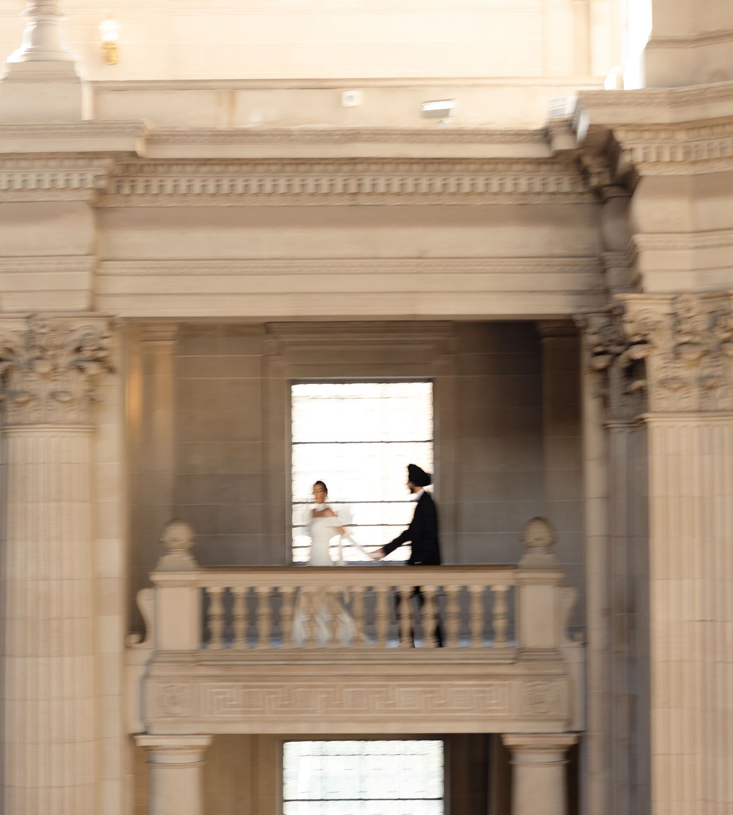 Wedding photoshoot in an elegant classical building with cream-colored columns and arches.