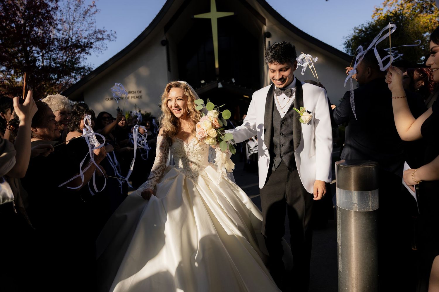 Wedding celebration outside a church with guests holding sparklers at dusk.