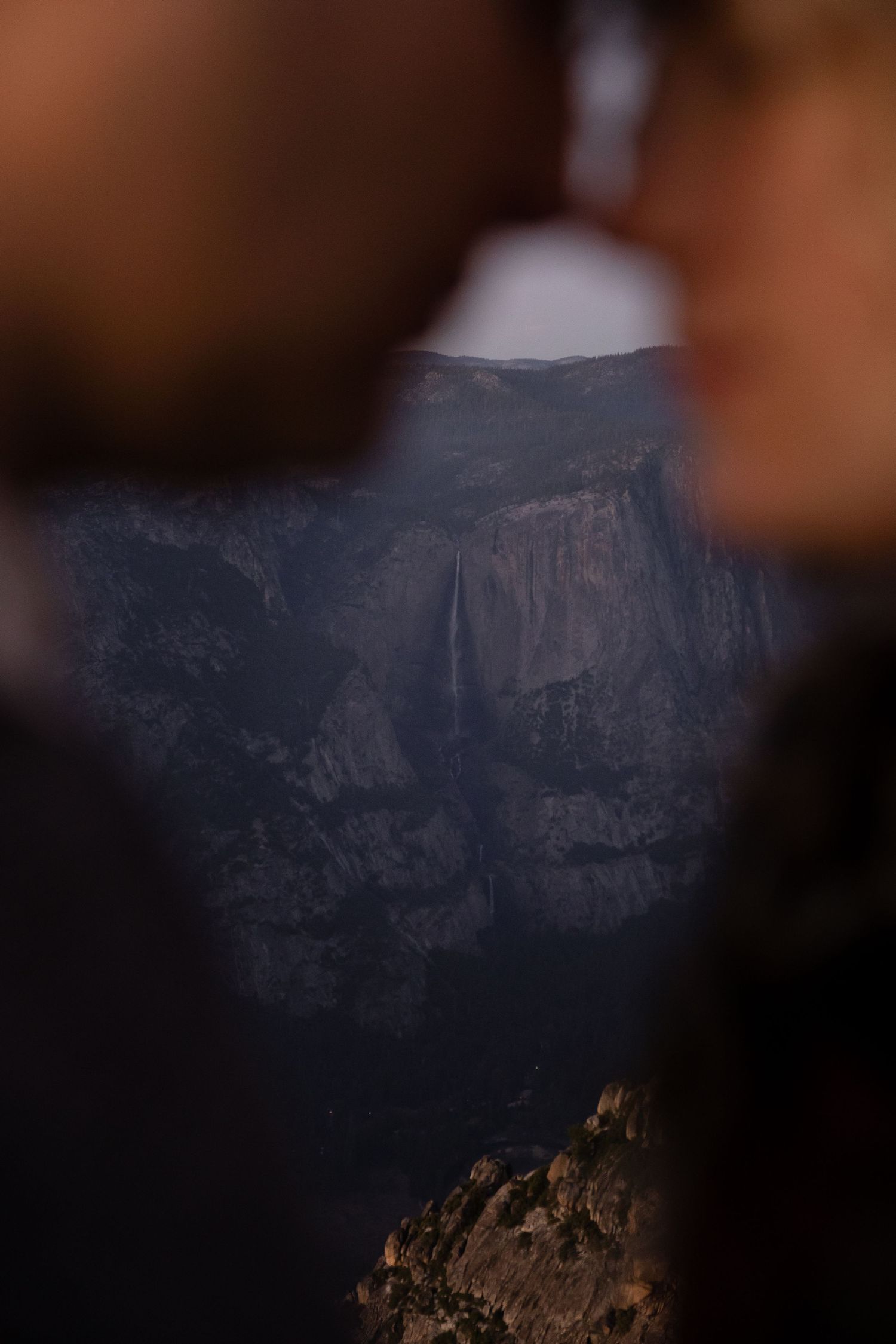 Dramatic granite cliffs of Yosemite Valley at sunset with dark shadows and rugged terrain.