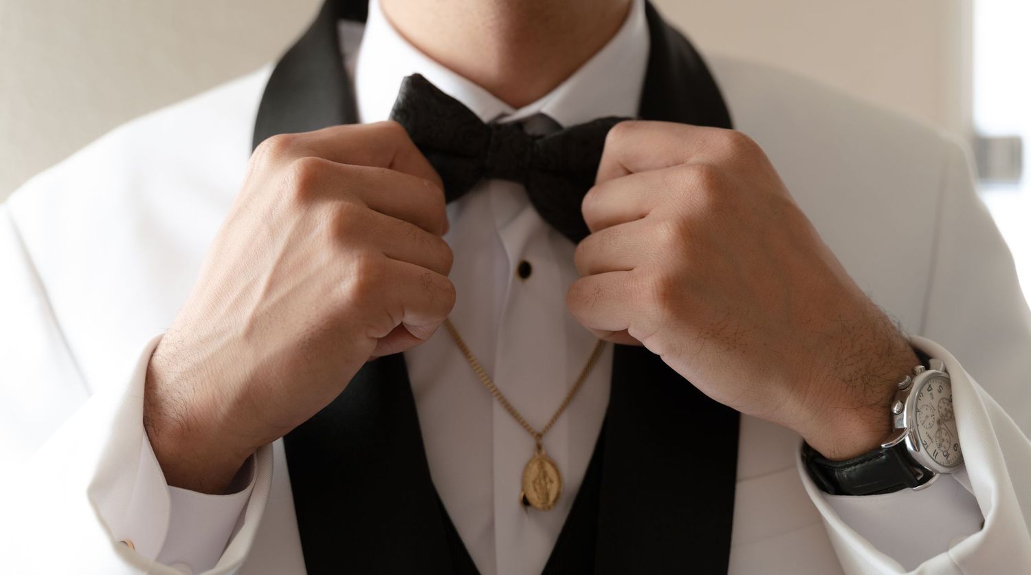 Adjusting formal bow tie and collar in white dress shirt.