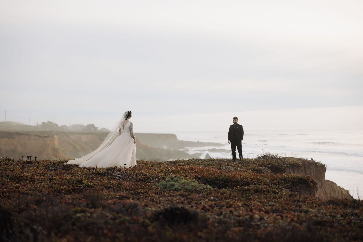 Silhouetted couple standing on dramatic coastal cliffs at sunset.